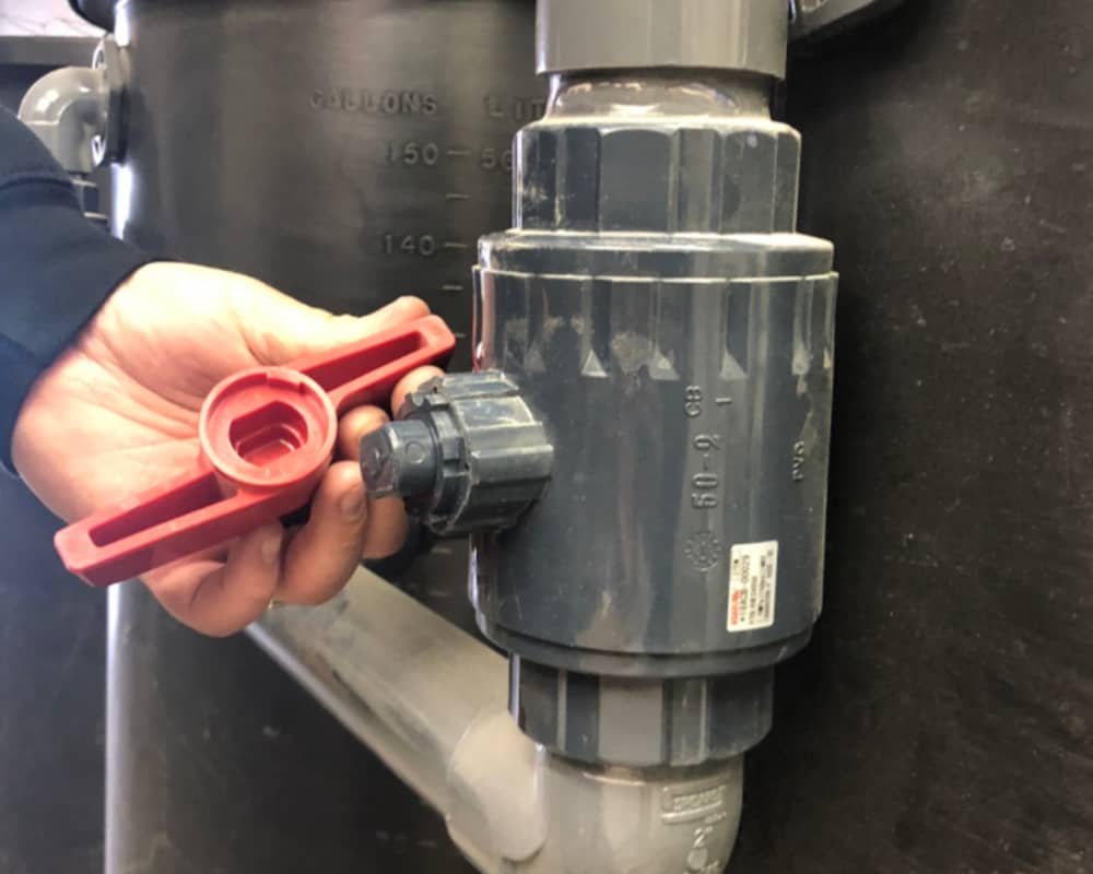 Technician operating a PVC ball valve on a pond filter tank