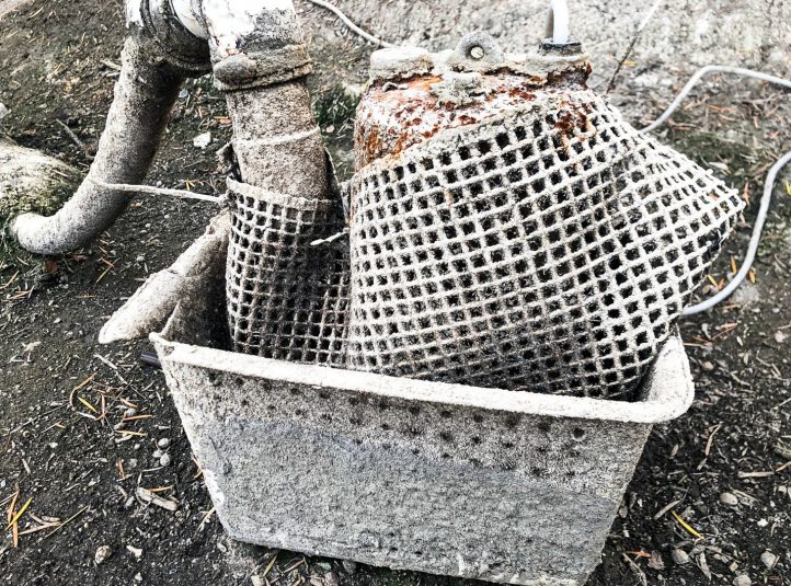 Pump intake and strainer basket caked with scale and debris