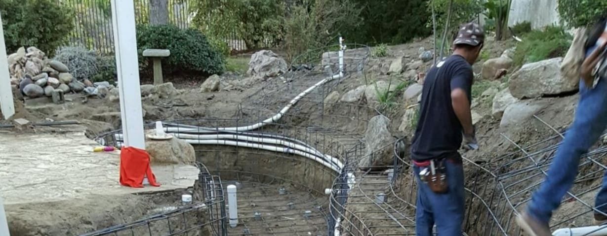 Koi Pros crew setting rebar and plumbing in a pond excavation