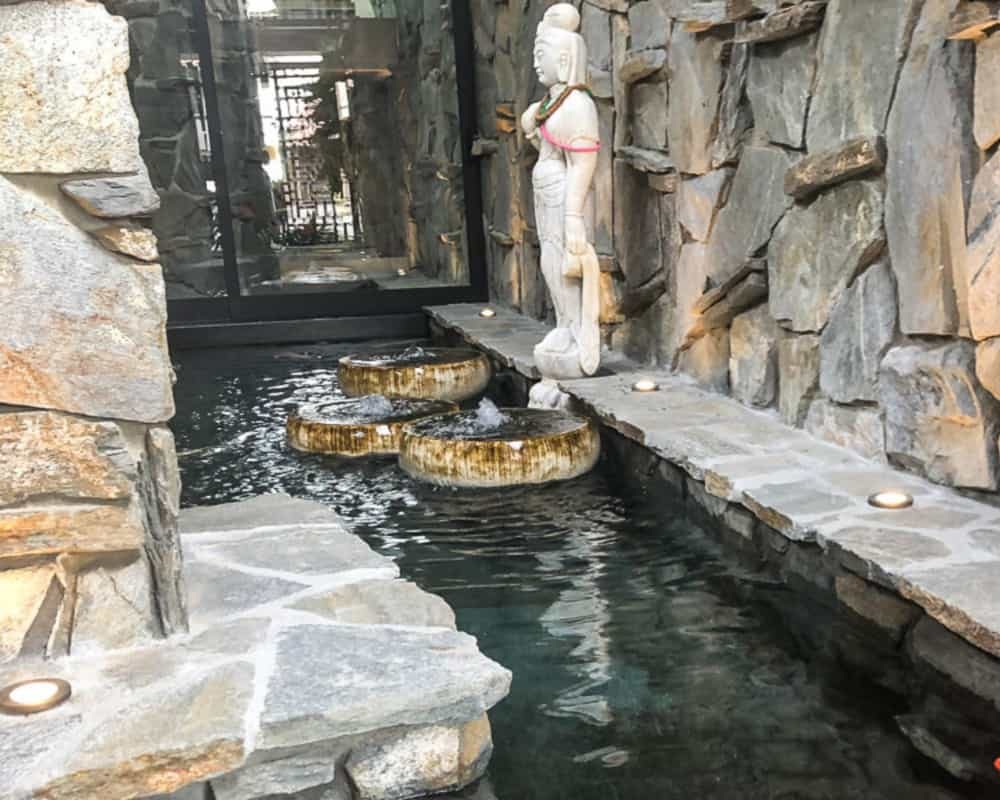 Courtyard koi pond with stone statue and three bubbling bowl fountains