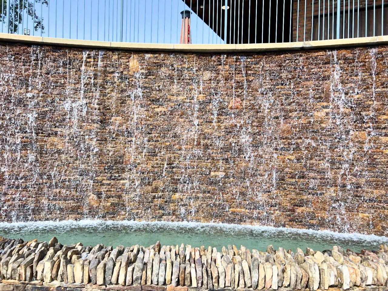 Curved stacked-stone water wall with cobble edge at a commercial site
