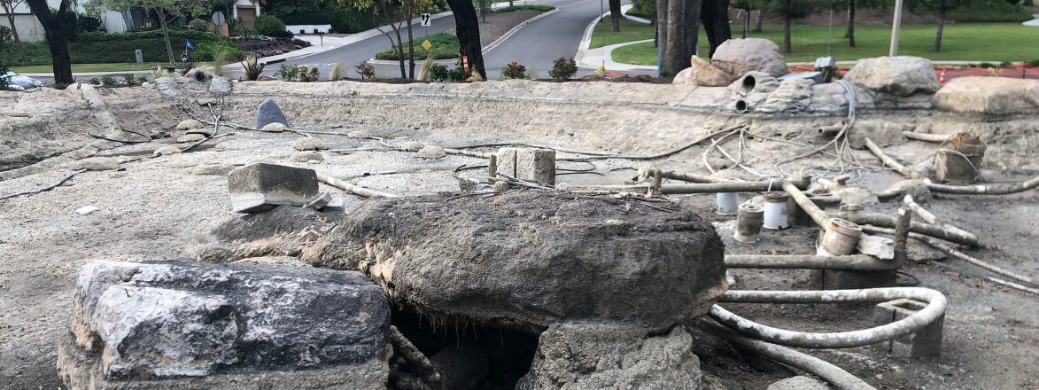 Lakeside rock waterfall stripped to its plumbing and conduit during a rebuild