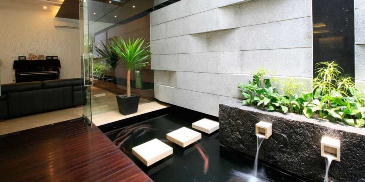 Indoor modern koi channel with floating pavers and twin spouts off a stone wall