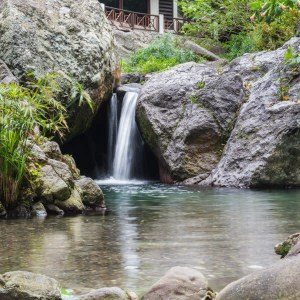 Natural waterfall between boulders into a clear pool
