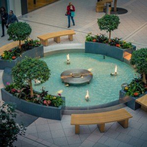 Round plaza fountain with planters and benches at a retail center
