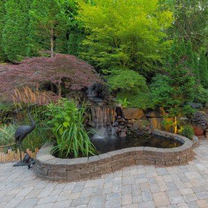 Raised pond with paver-block wall, waterfall and crane statues