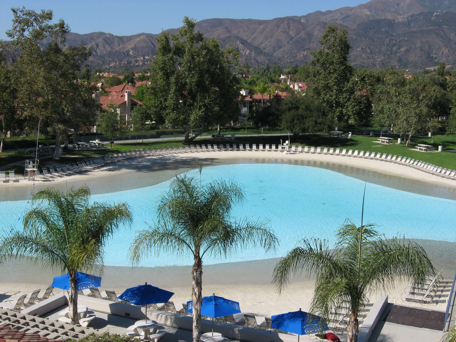 Community swimming lagoon with sand beach, palms and the Santa Ana Mountains behind
