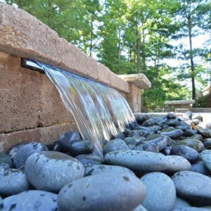 Sheer descent spillway pouring over river pebbles