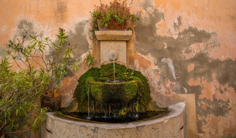 Spanish-style wall fountain with a mossy basin