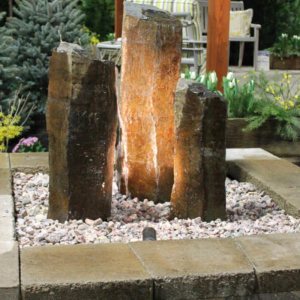 Lit basalt column fountains in a paver-edged pondless basin