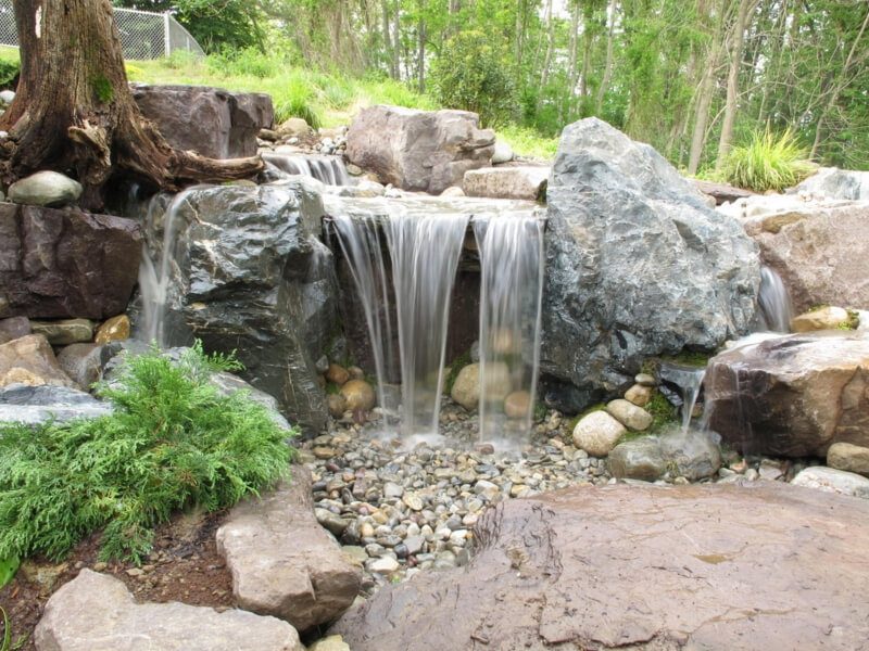 Boulder waterfall and stream through a shaded garden