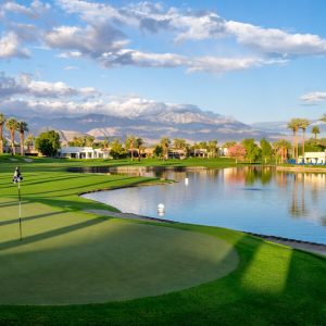 Golf course lake lined with palms below the desert mountains, Coachella Valley