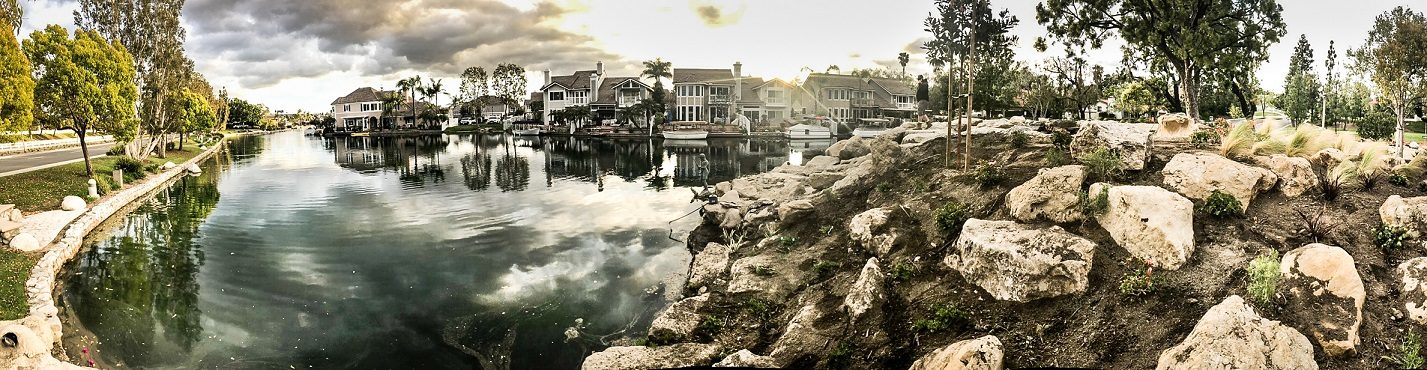 Panorama of a community lake with new boulder shoreline and plantings, Orange County
