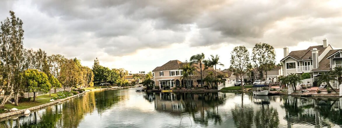 Panorama of a community lake with lakefront homes and boats under a cloudy sky