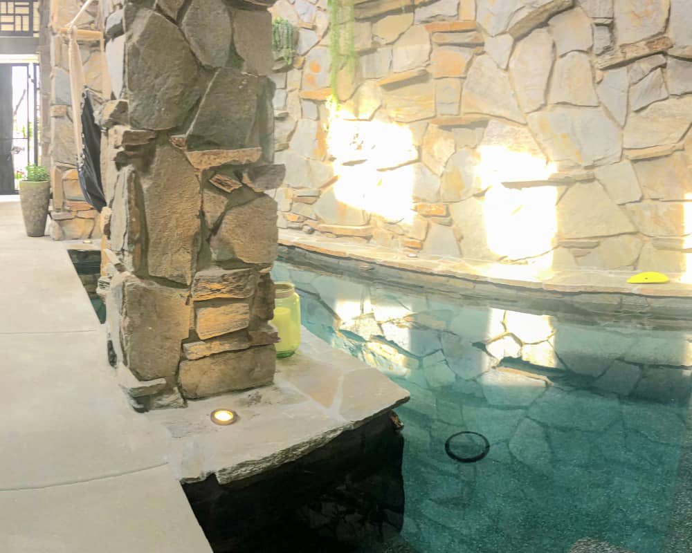 Stone-walled courtyard koi pond with lit stone pillar and clear water