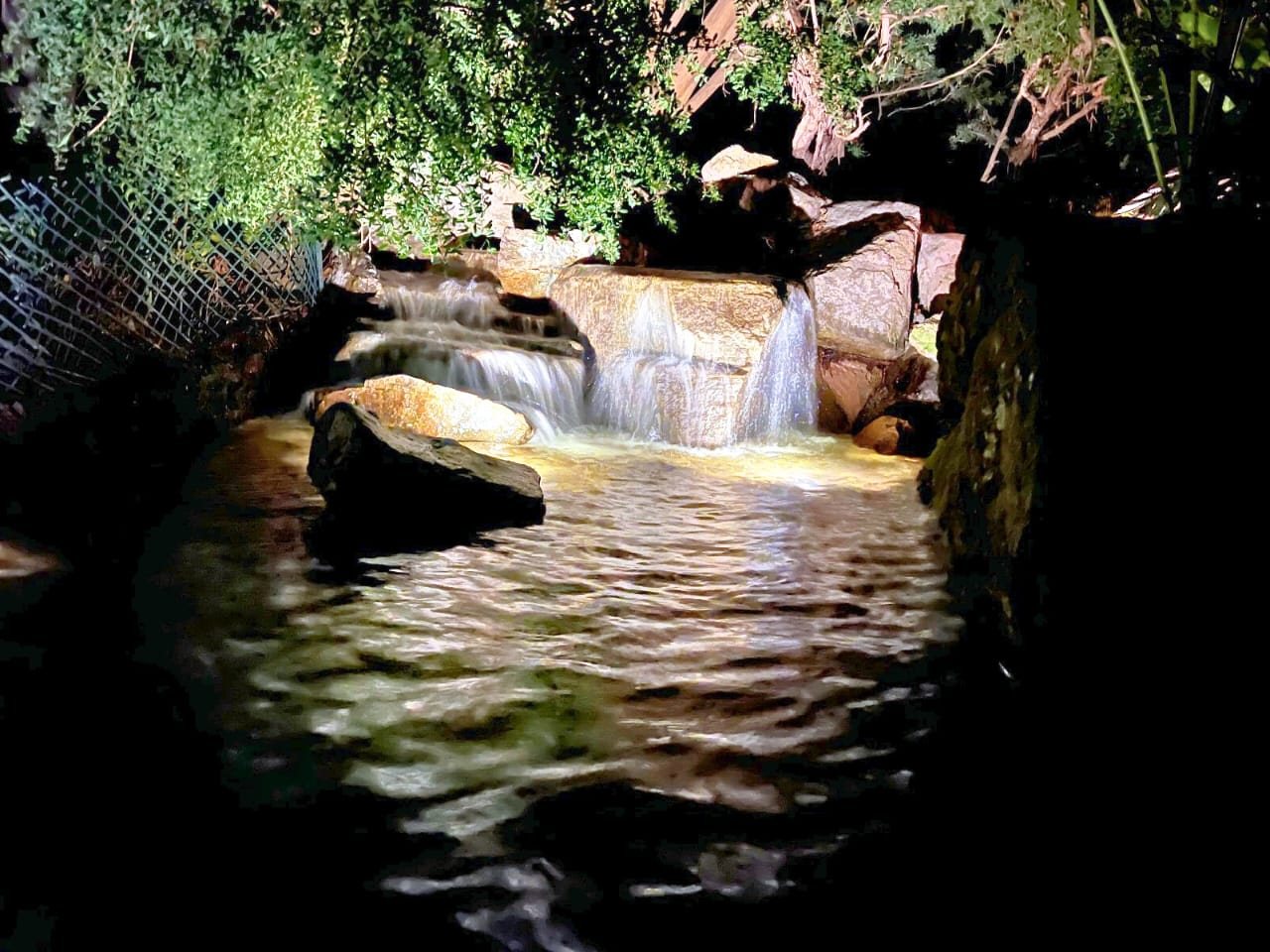 Multi-tier estate stream and waterfall lit at night