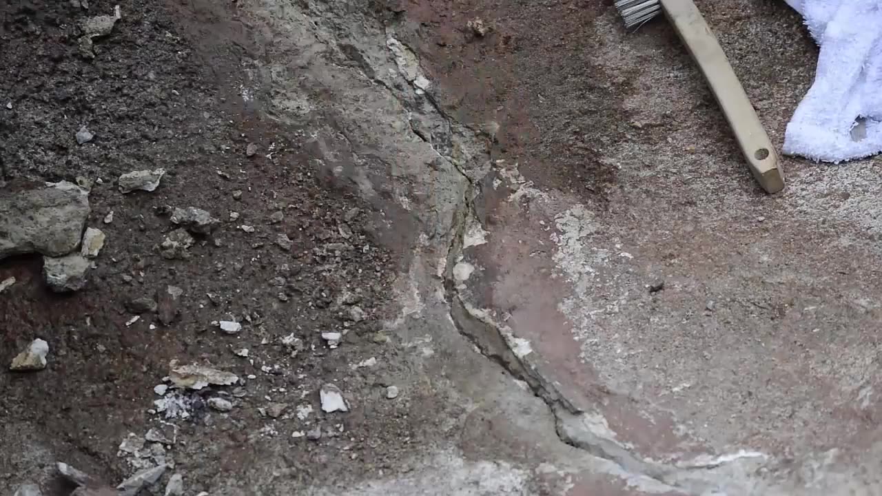 Technician grinding cracks in a concrete stream bed before patching