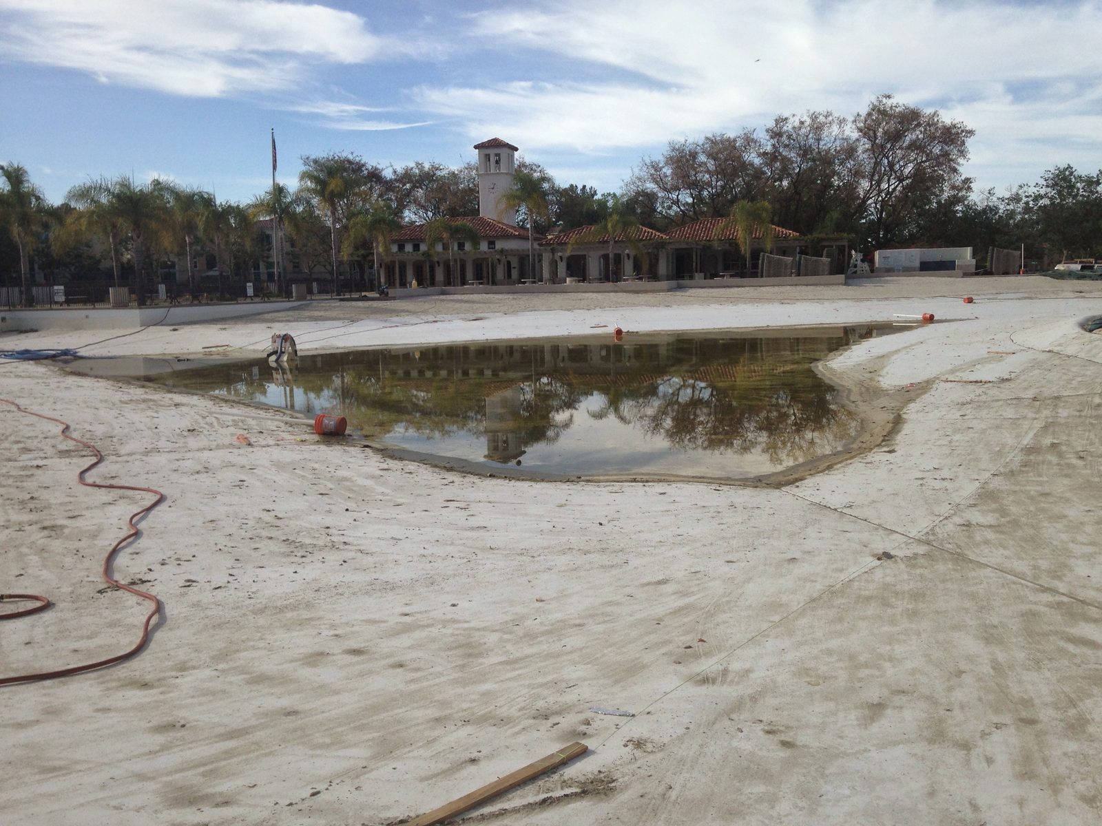 Community lagoon drained to a puddle before relining, clock tower behind