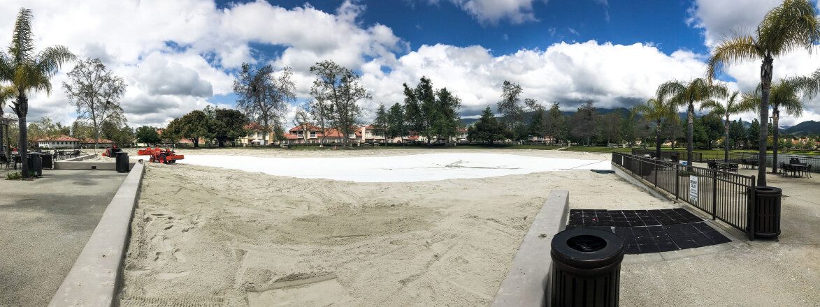 Panorama of a drained community lagoon with new white liner being covered in sand