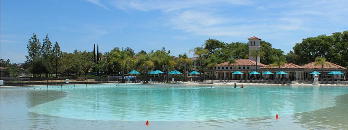 Refilled turquoise community lagoon with beach club and umbrellas behind
