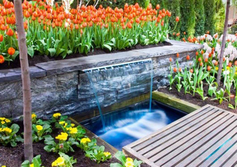 Sheer-descent spillway into a stone basin in a garden bed