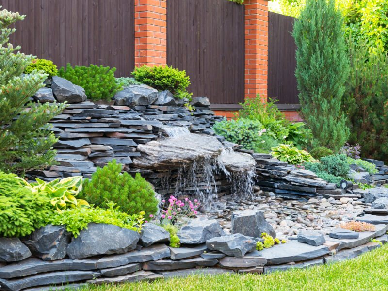 Stacked slate waterfall with conifers and perennials
