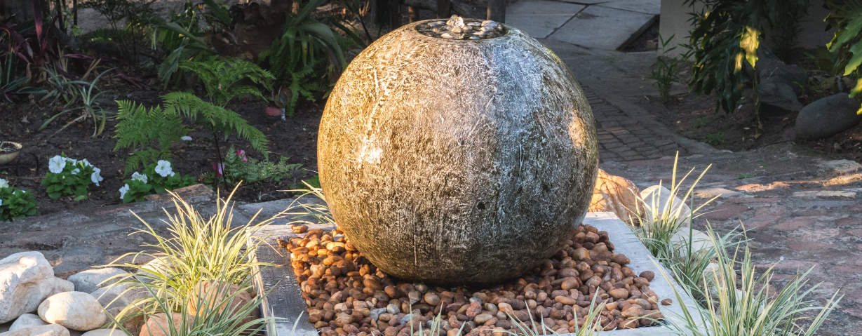 Granite sphere fountain set in a garden bed